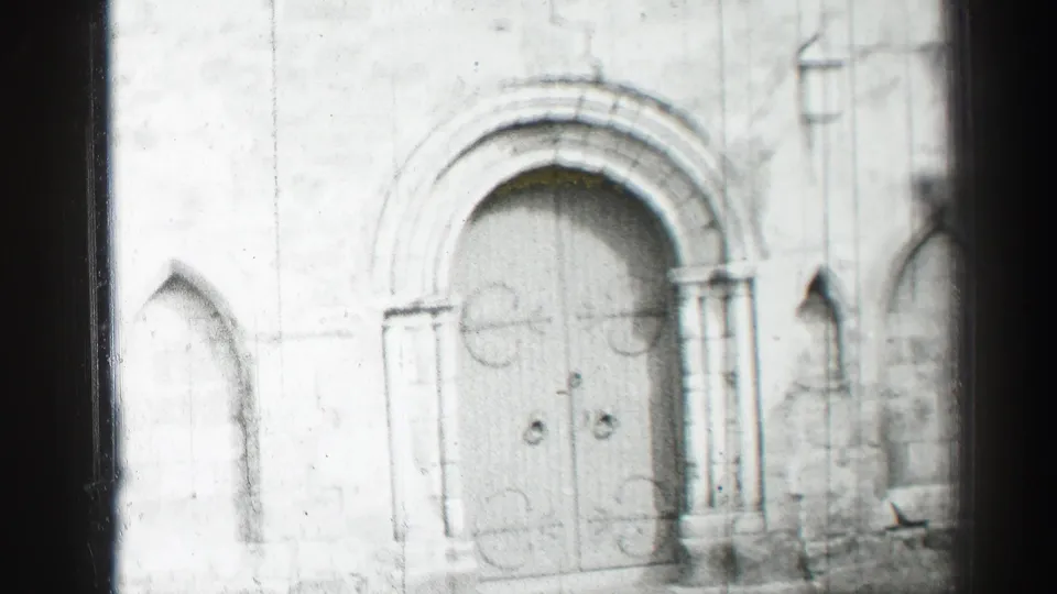 1952 Edinburgh home-movie frame showing a weathered stone church entrance with arched double doors and Gothic details.