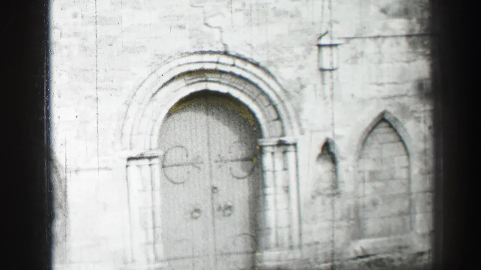 Black-and-white 8mm view of an Edinburgh church facade, centered on the arched doors and surrounding stonework.