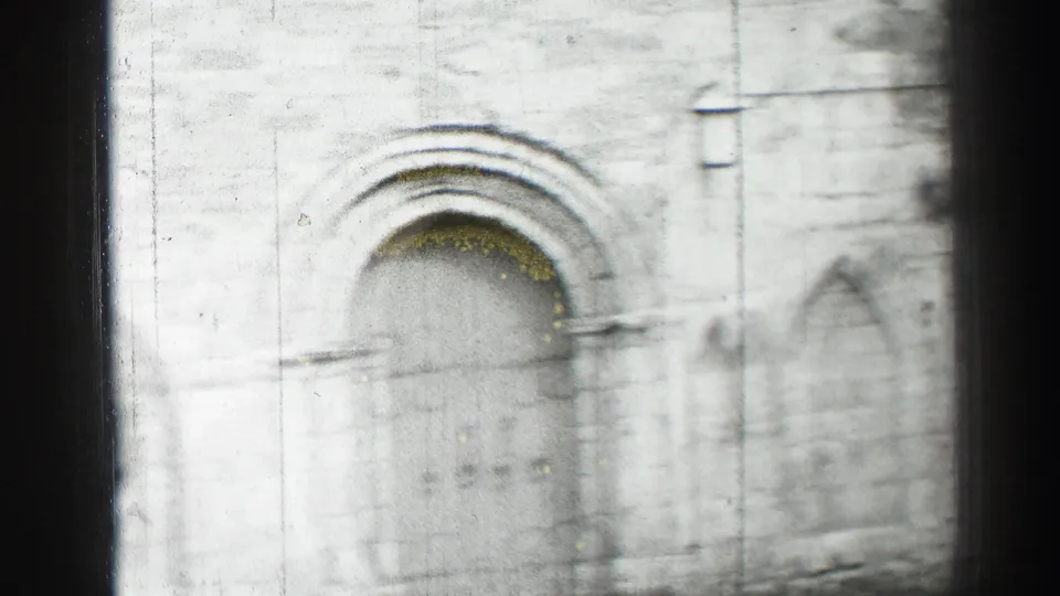 Soft 1952 Edinburgh 8mm frame showing the church entrance, arched stone surround, and weathered wall surface.