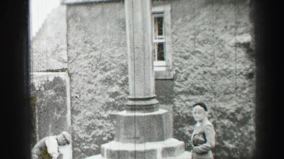 1952 Edinburgh frame with a woman standing near a column as a man bends to work beside the stone building.