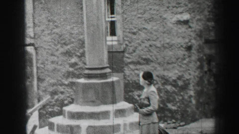 A visitor stands beside rough stonework and a projecting column in an Edinburgh castle setting, from 1952 8mm footage.