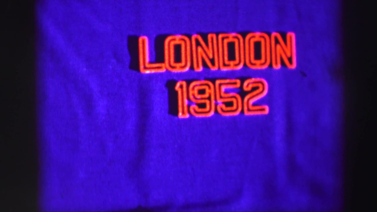 1952 home-movie title card showing red outlined London 1952 lettering against a purple fabric backdrop.