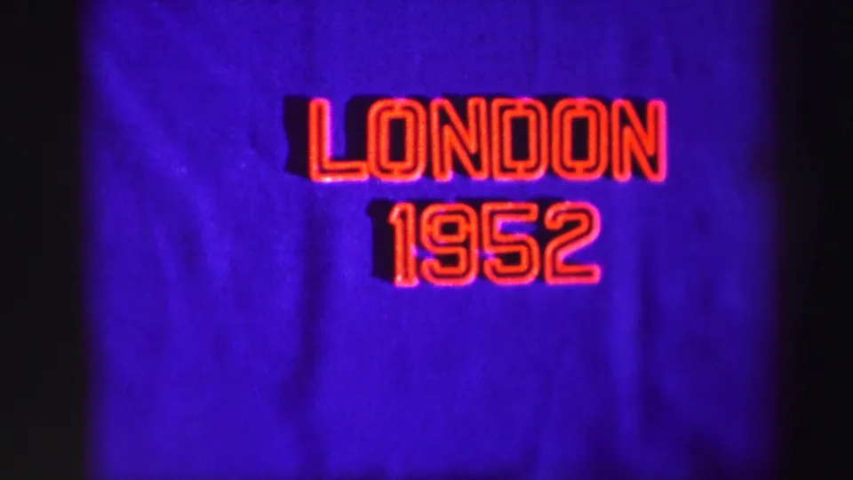 Final frame of the static 8mm title card, showing London 1952 in red outline on purple fabric with dark side shadowing.