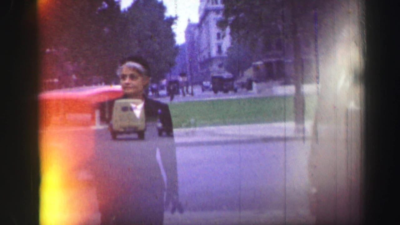 1952 Edinburgh street view with a pedestrian, vintage cars, stone architecture, and heavy film flare at the frame edge.