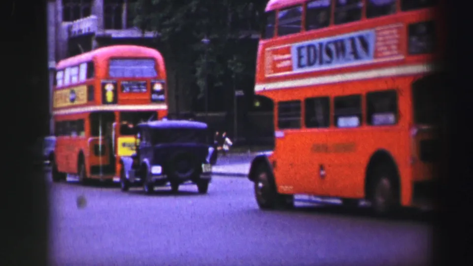 1952 Edinburgh street traffic with red double-decker buses, a dark vintage car, trees, and an EDISWAN advertisement on a bus side.