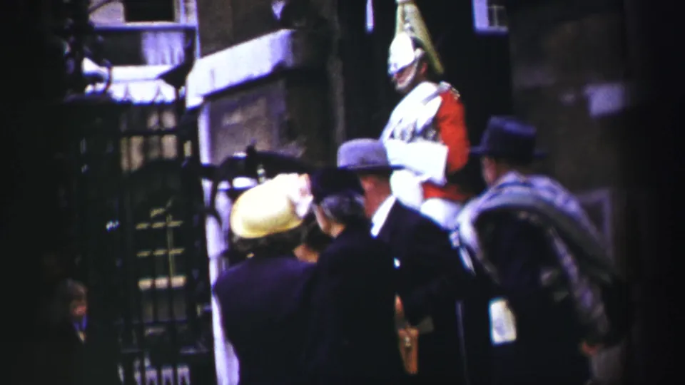 Mounted ceremonial soldier in red and white uniform near pedestrians in hats on an Edinburgh street, based on supplied 1952 metadata.