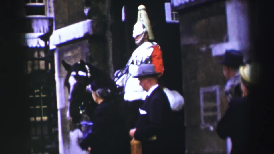 A mid-century Edinburgh tourist frame shows the mounted guard, horse, gate, and nearby visitors in hats and dark coats.