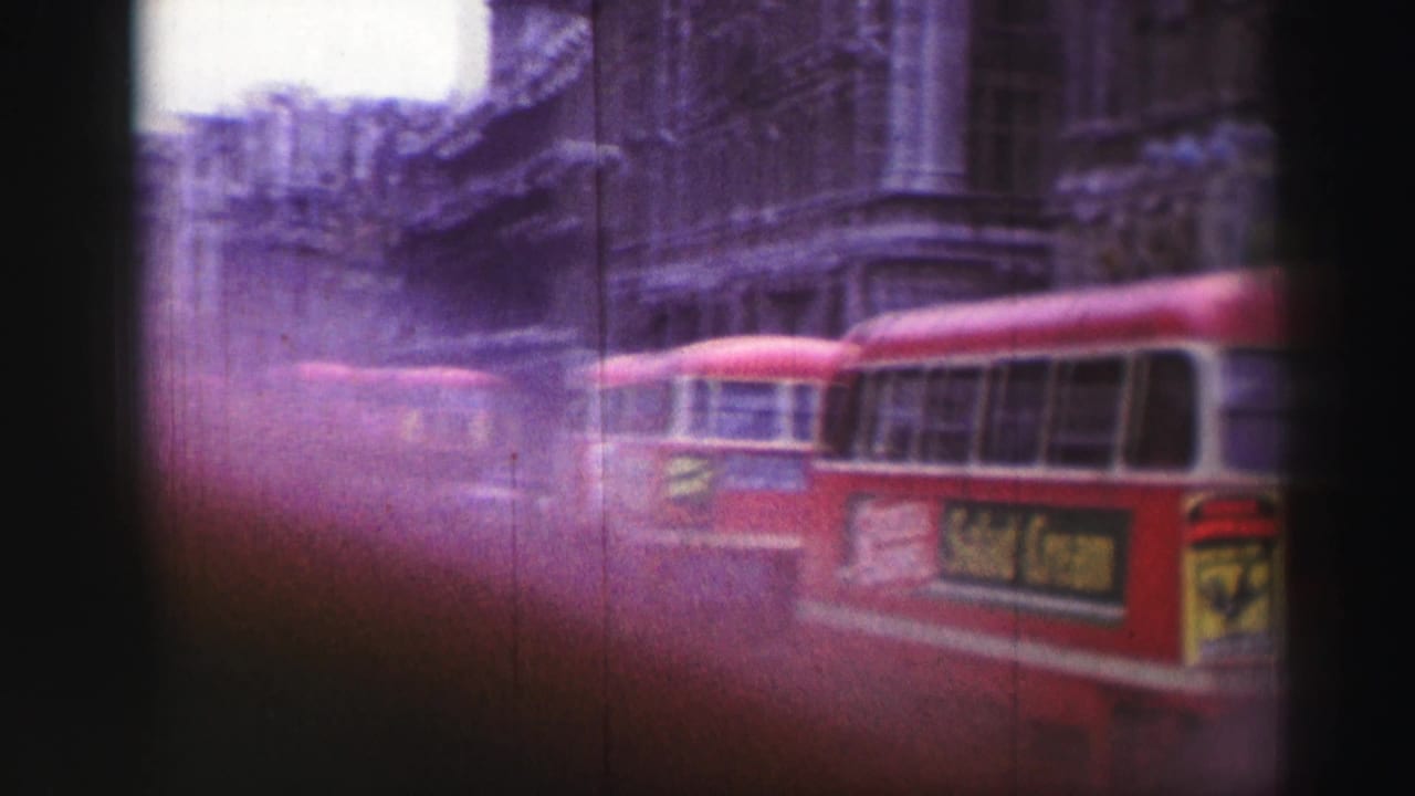 1952 Edinburgh street view with red buses moving past stone buildings, softened by magenta cast and light leak.