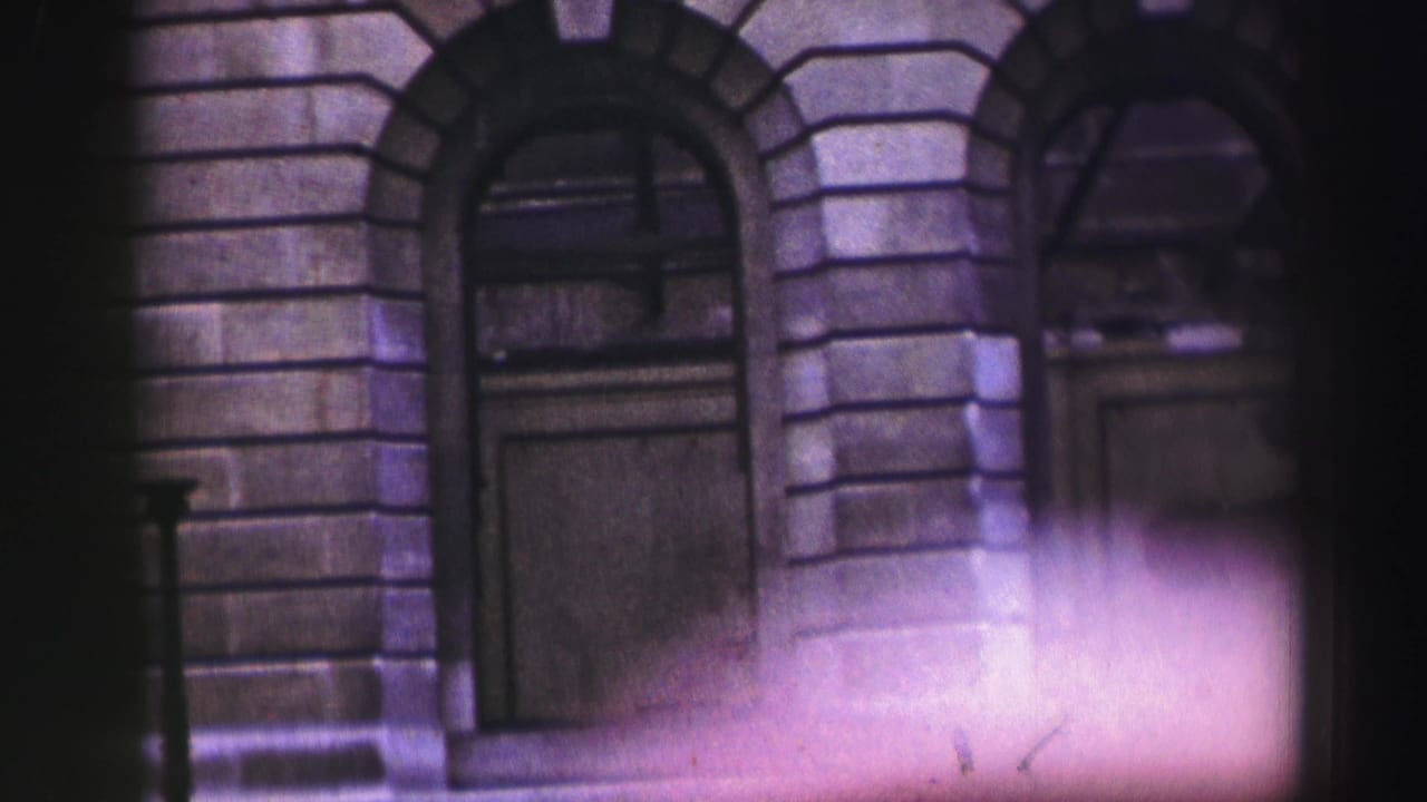 Stone facade with arched doorways and a soft light flare across the lower frame.