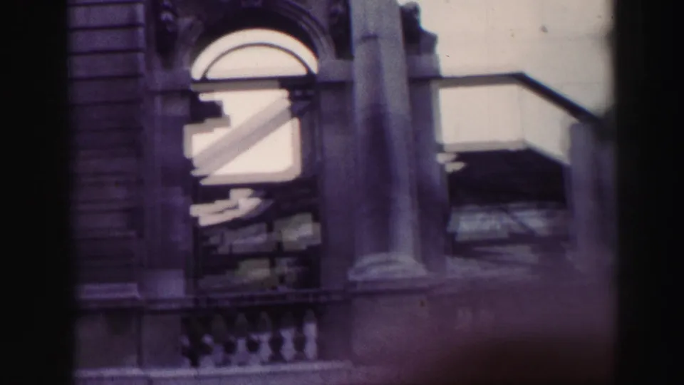 1952 Edinburgh travel footage frame showing a stone arch, column, balustrade, and layered railings in a weathered facade.