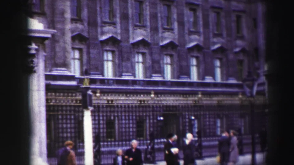 1952 Edinburgh home-movie frame showing pedestrians near iron railings and a formal stone facade.
