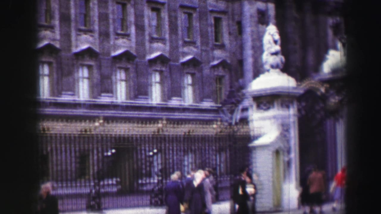 1952 Edinburgh street view with pedestrians near an ornate entrance, iron gates, and stone architecture.