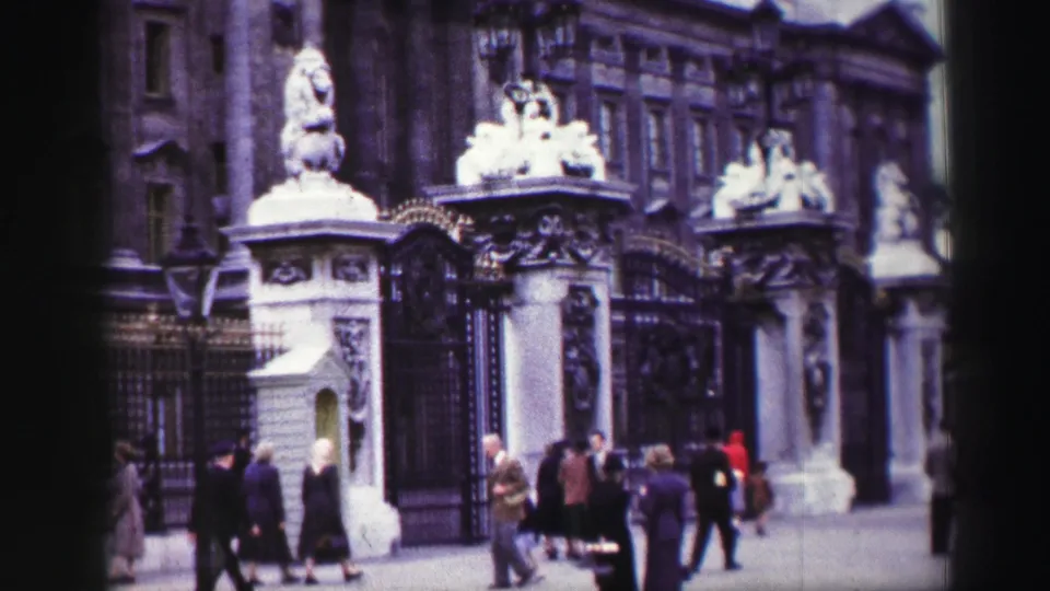 1952 Edinburgh home-movie frame with ornate gates, sculpted lion figures, ironwork, and sidewalk pedestrians.