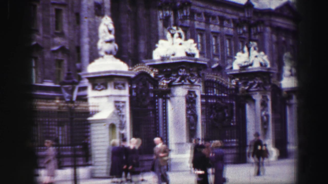 Reported 1952 Scotland home-movie frame showing an ornate gate, stone pillars, statues, and pedestrians near the entrance.