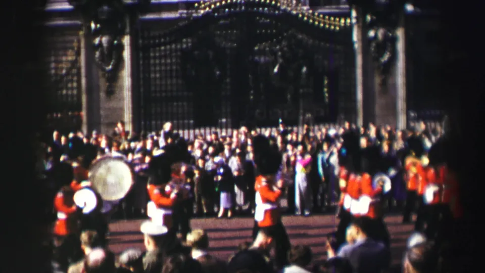 Reported 1952 Scotland frame showing spectators watching guards in red tunics, with a large drum visible in the foreground.