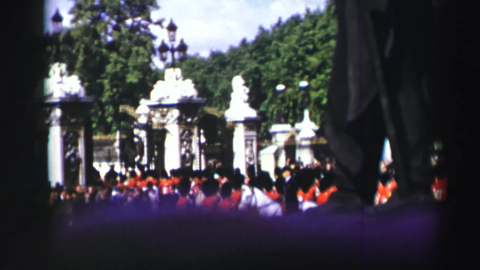1952 Edinburgh frame with a crowd watching red-uniformed soldiers near decorative stone gates, trees, and lamp posts.