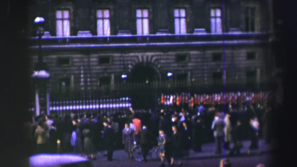 1952 Edinburgh frame showing spectators and red-uniformed soldiers outside a large historic building with railings and an arched entrance.