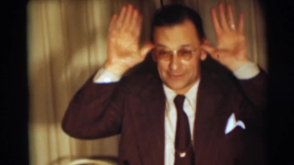 The man raises both hands near his head in a playful pose, continuing the candid 1954 Pennington home-movie moment.