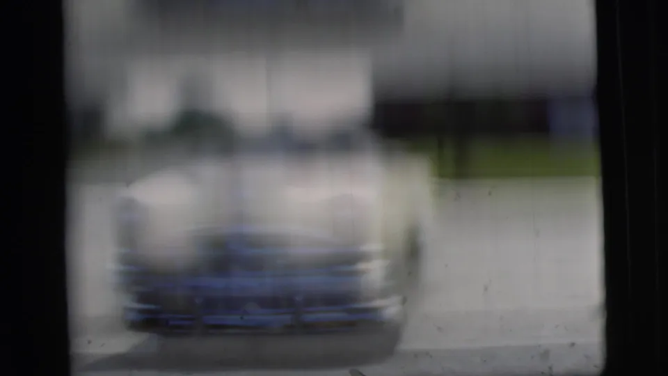 A motion-blurred 8mm frame shows the yellow convertible shifting in the driveway, with the background softened by camera or subject movement.