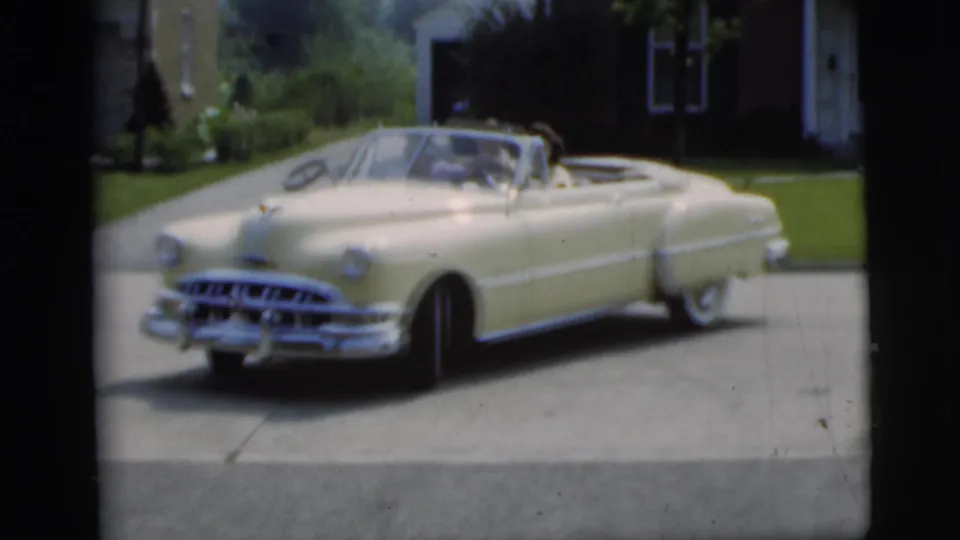 Cream convertible in Pennington, New Jersey, backed partway from a suburban driveway in 1955 home-movie footage.