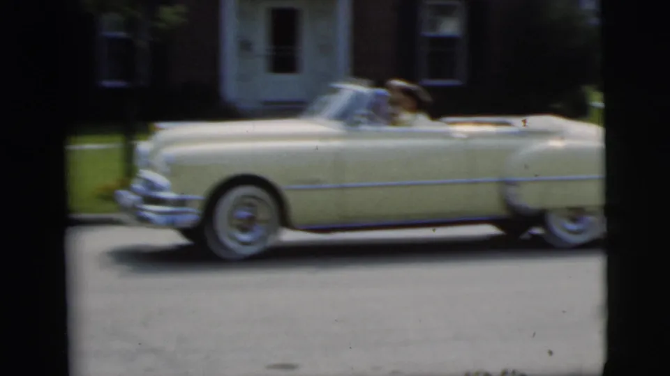Motion-blurred side view of the cream convertible continuing along the driveway in 1955 Pennington home-movie footage.