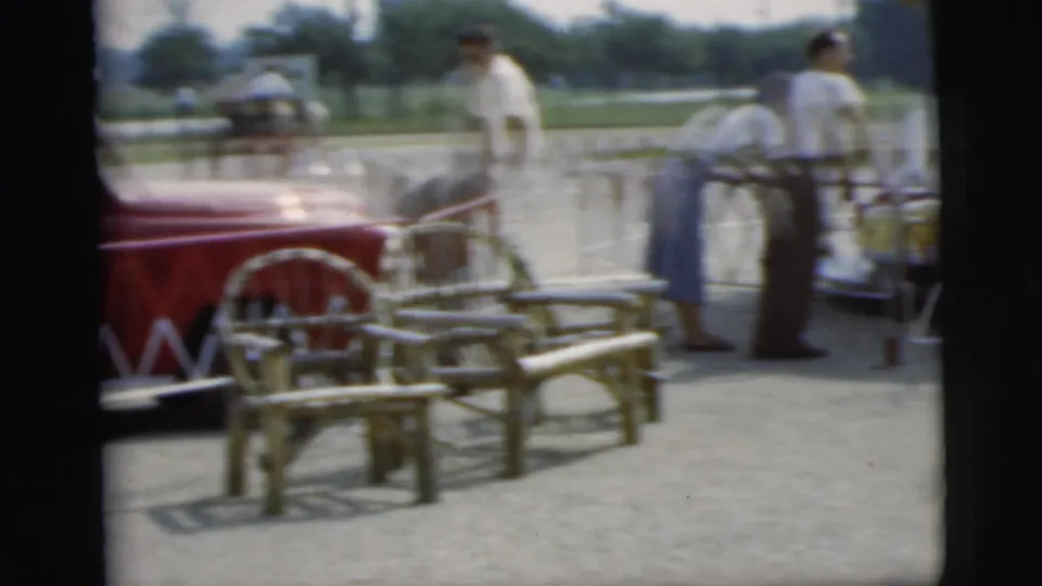 Adults gather near picnic tables and the red fire truck at a Pennington outdoor community event in the 1955 clip.