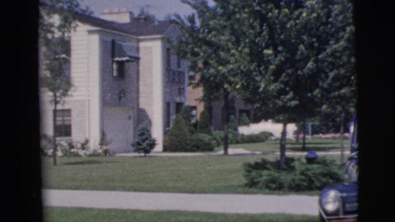 1955 Pennington residential exterior with a pale building, green lawn, sidewalk, trees, shrubs, and the edge of a parked car.