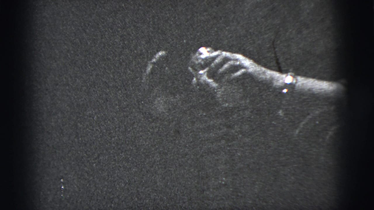 1956 New York City frame with a cigarette held near a shadowed figure, rendered in dark grainy 8mm texture.