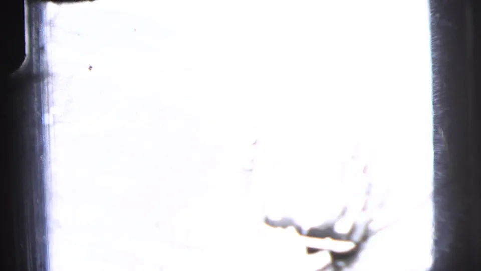 Overexposed winter-looking 8mm frame from the same 1956 New York City clip, with snow brightness and a partial vehicle shape.
