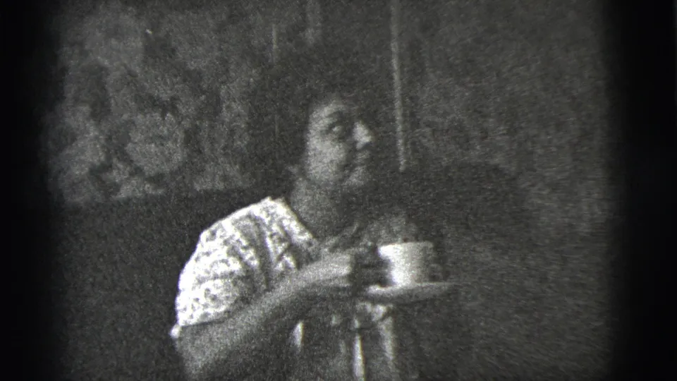 At the end of the clip, the woman holds her cup and saucer and turns slightly to the side in the 1956 New York City interior.