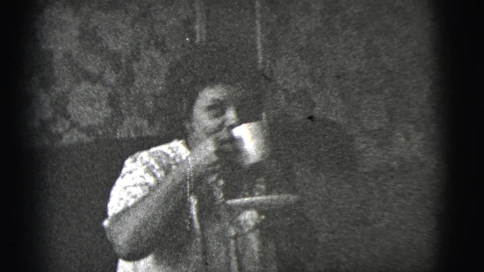 The woman remains seated with the cup near her face and a saucer in hand, framed by dark 8mm contact-sheet edges.