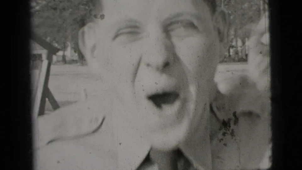 Close 1956 New York home-movie frame of a young man leaning into the lens and making a playful exaggerated face.
