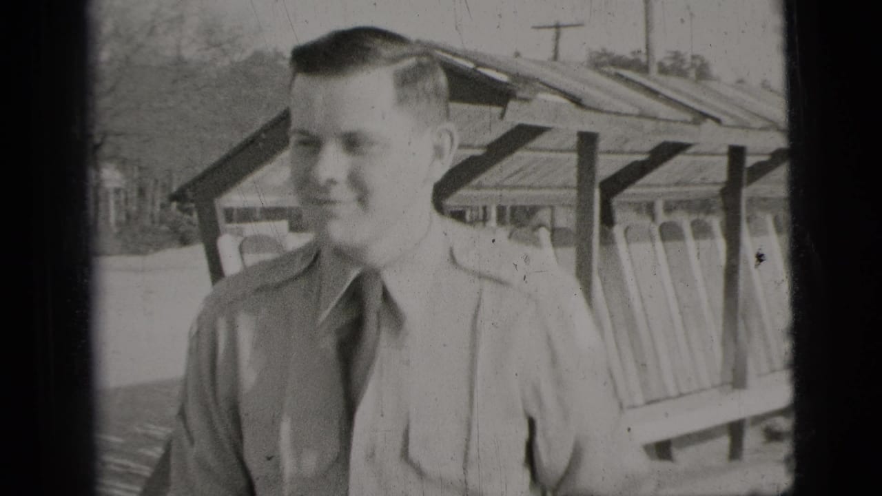 Closer 1956 New York City frame of the young man smiling in a light shirt and dark tie beside the shelter structure.