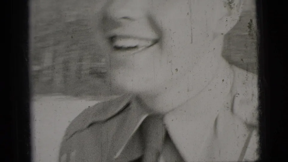 Soft close-up from the 8mm clip crops tightly on the man's smile, jaw, shirt collar, and shoulder.