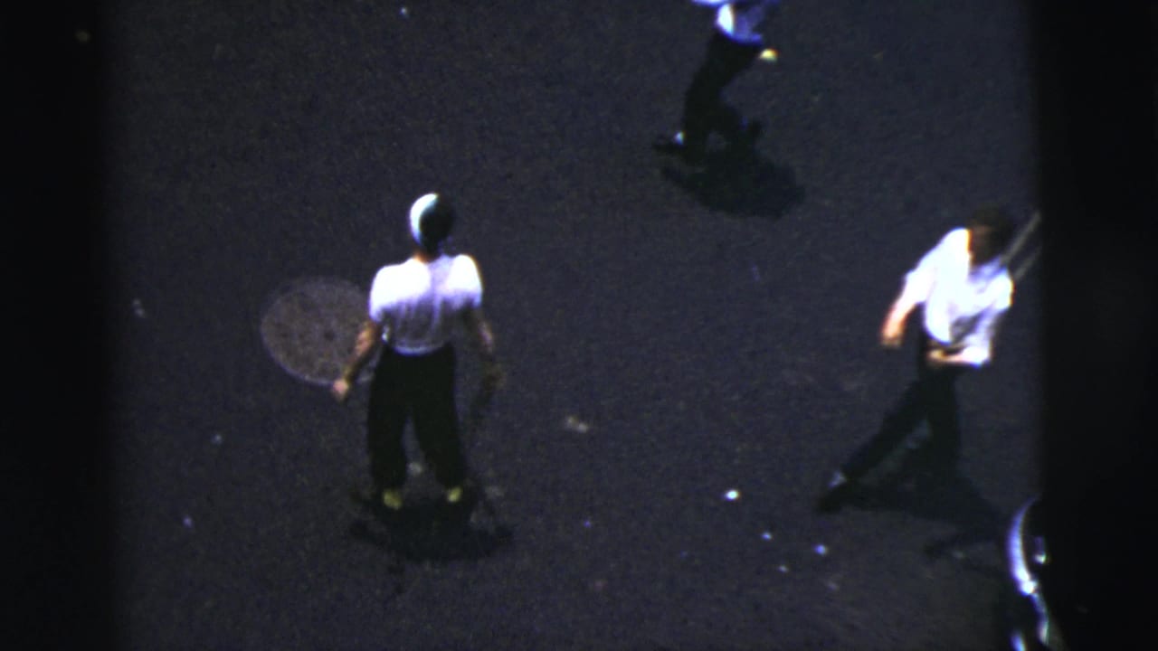 Boy stands on the street while another participant moves at the edge of frame.