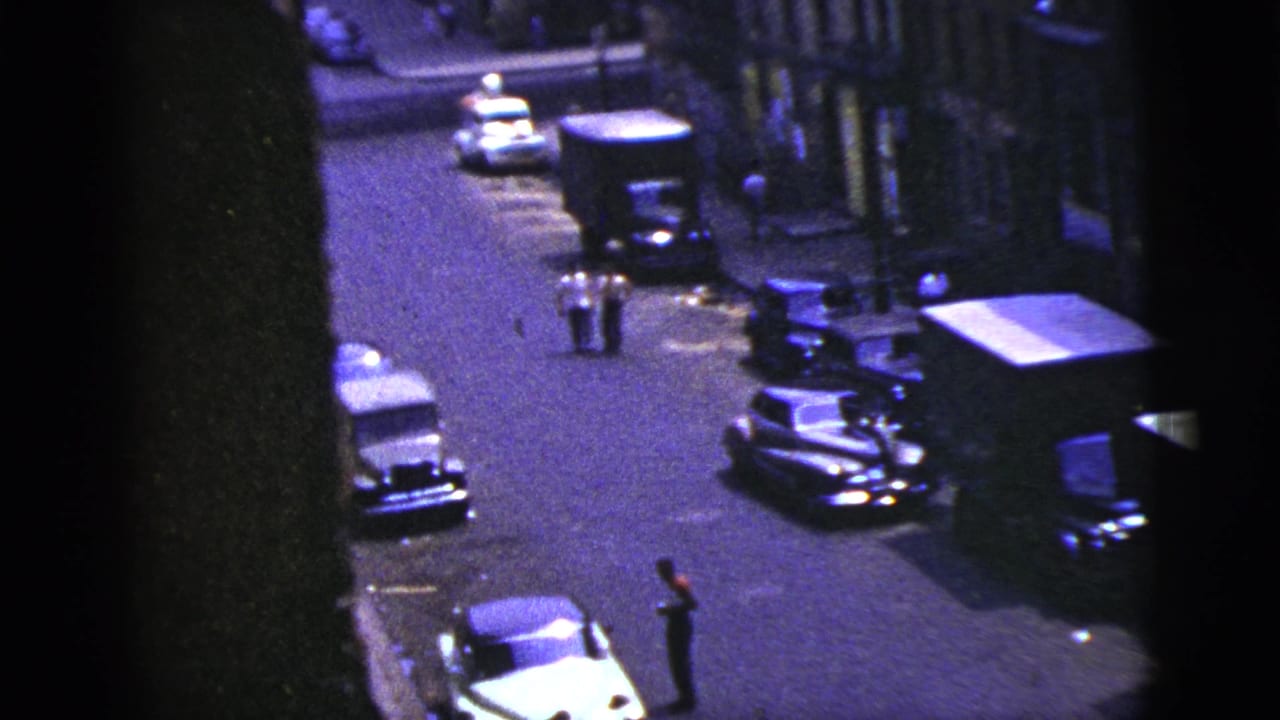 Elevated view of a New York City street in 1956, with curbside cars, a truck, and small pedestrian figures.
