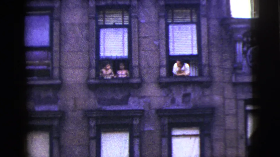 1956 New York City frame of apartment windows, with two people at one window and a person in a white shirt leaning from another.