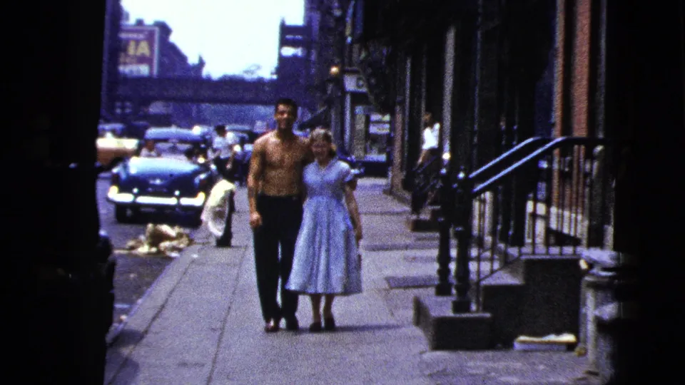 The man and woman remain centered on a New York City sidewalk, framed by dark doorway edges, stoops, and midcentury cars.