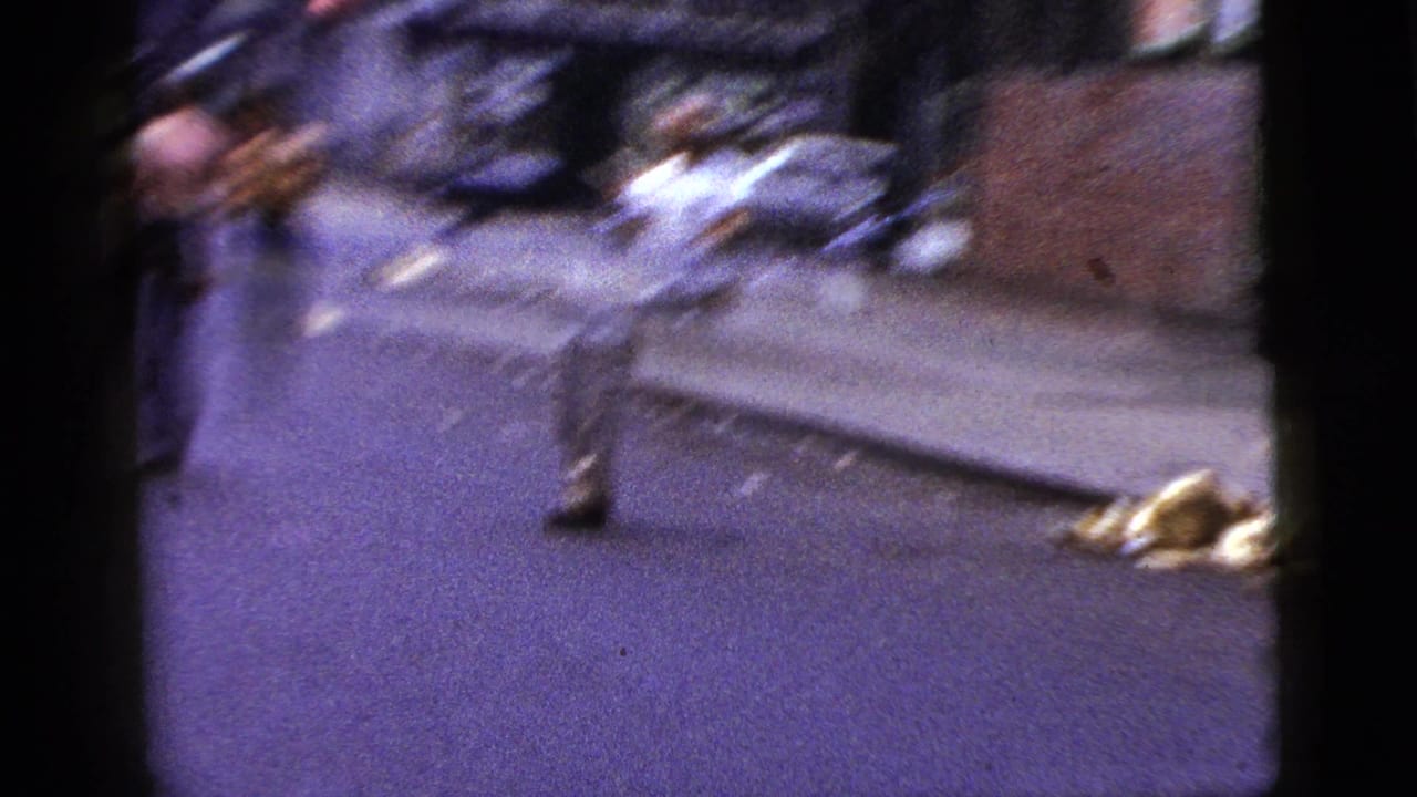 1956 New York City street footage with motion blur as a man moves near the curb beside a sidewalk and scattered street debris.