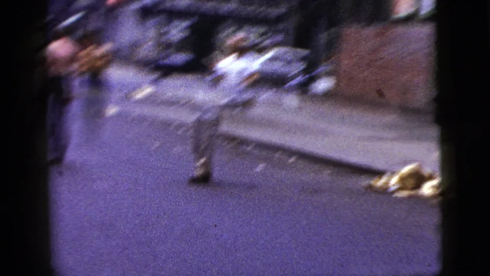 1956 New York City street footage with motion blur as a man moves near the curb beside a sidewalk and scattered street debris.