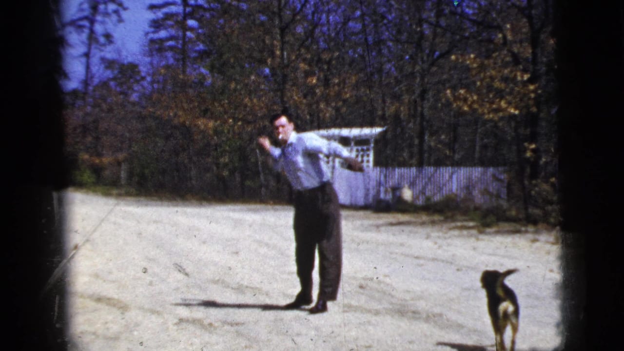 Man leans into a throw on a dirt road with a small dog standing in the foreground.