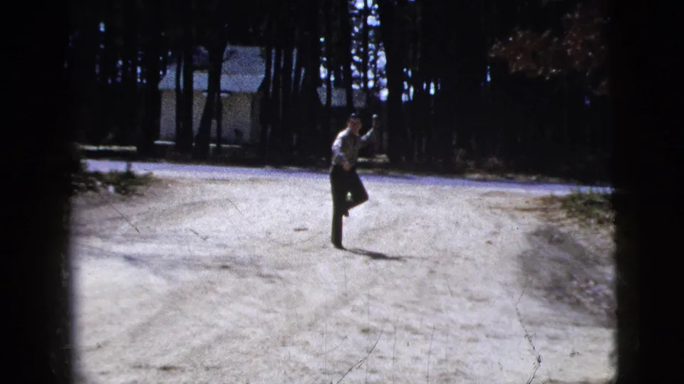 The man lifts one leg and keeps his arm raised, giving the movement a playful home-movie quality.