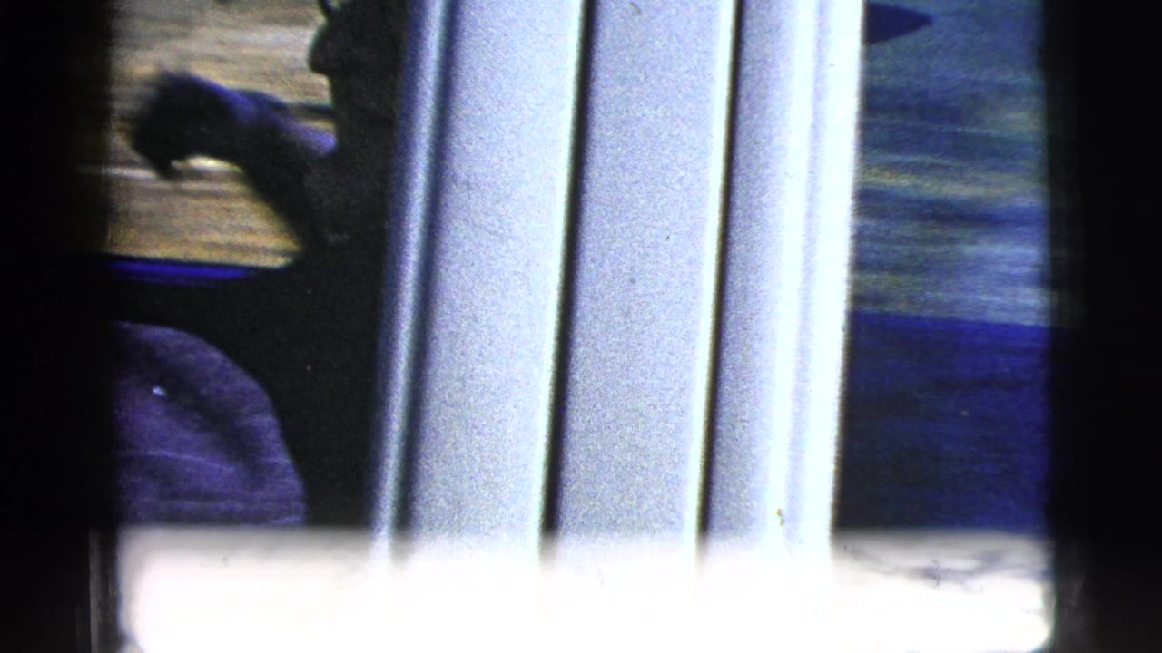 Blurred partial view of a person and car interior framed by dark film edges.