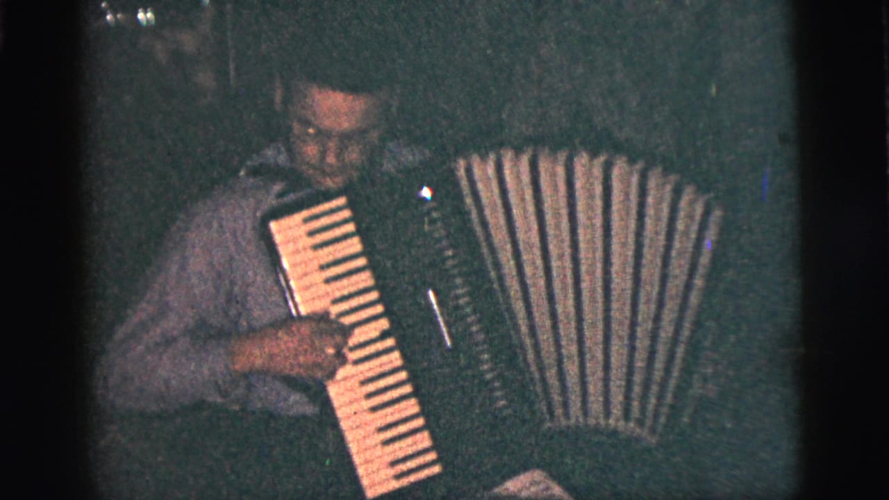 Man playing an accordion in a dark indoor room.
