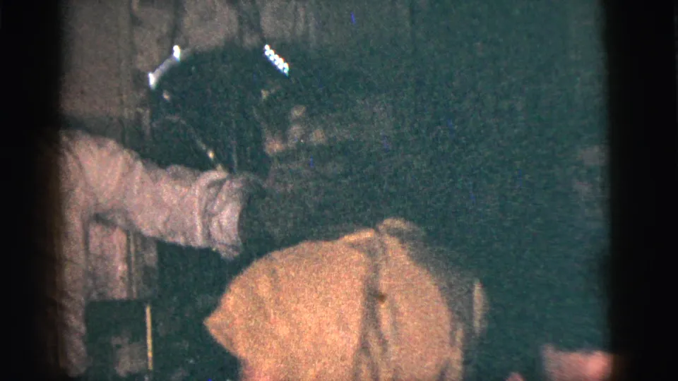 In the final frame, the woman bends forward in the yellow dress while the man in a light shirt extends an arm beside her in the dark room.