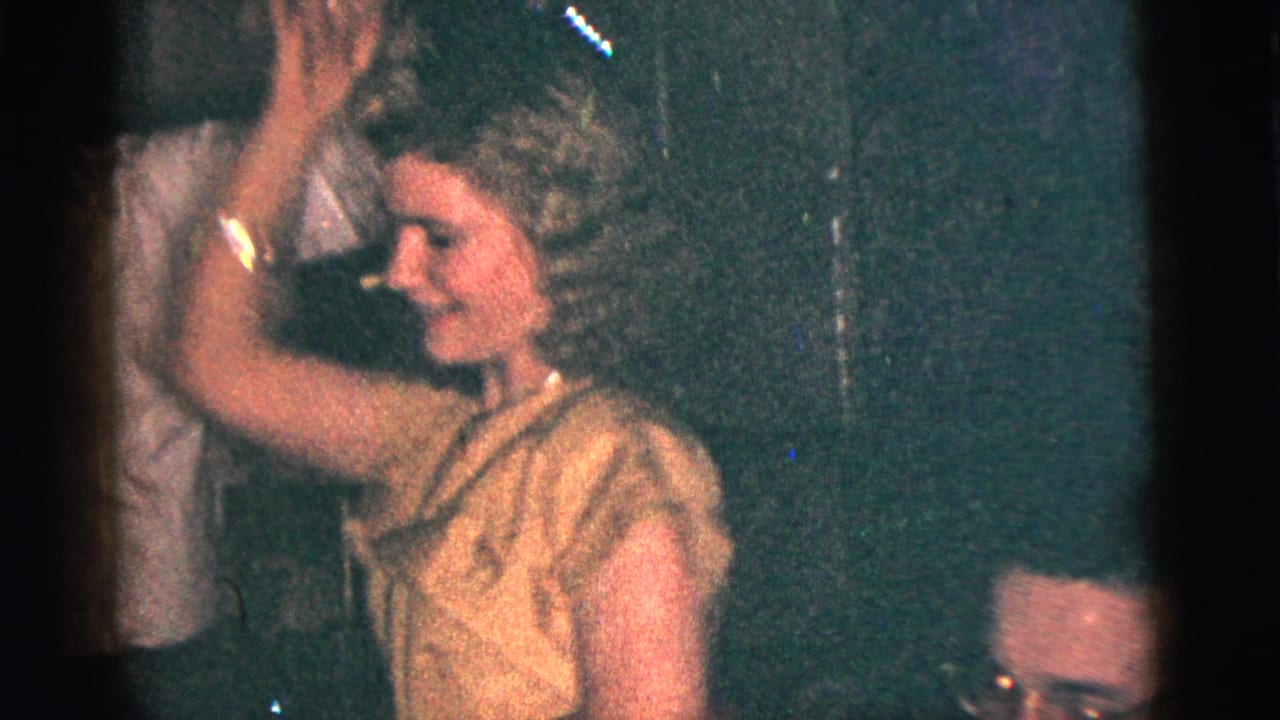 Woman in a light dress dancing closely with a man in a dim interior.