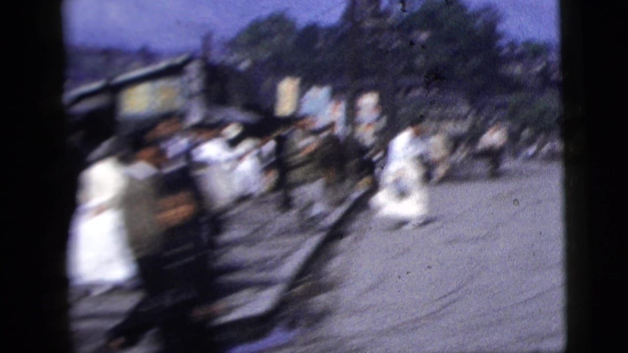 Motion-blurred 1958 New York City street view with several pedestrians and a dark truck-like vehicle near the curb.