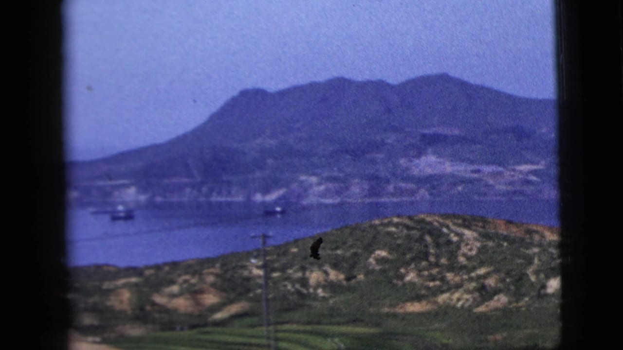 Distant mountain shoreline beyond water, with boats and a utility pole in the foreground.