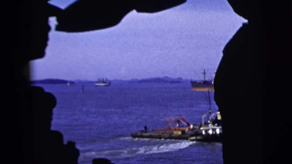 New York City harbor traffic in 1958, with a small workboat moving across blue water under a dark frame.