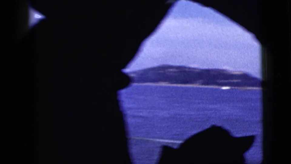 New York City harbor in 1958, with distant land and water viewed through a dark window-like frame.